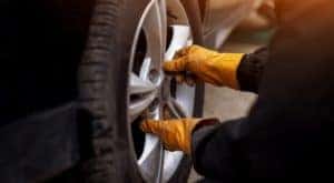 A gloved mechanic is shown adjusting a tire.