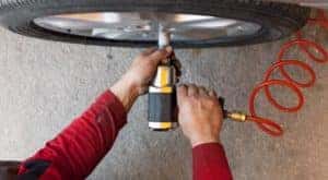 A top-down view shows a mechanic in a Cincinnati tire shop using an impact wrench on a tire.