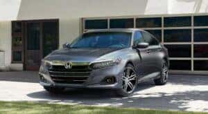 A grey 2021 Chevy Malibu is shown from the front parked in front of a building.