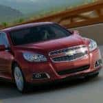 A red 2013 used Chevy Malibu LTZ is driving over a bridge.