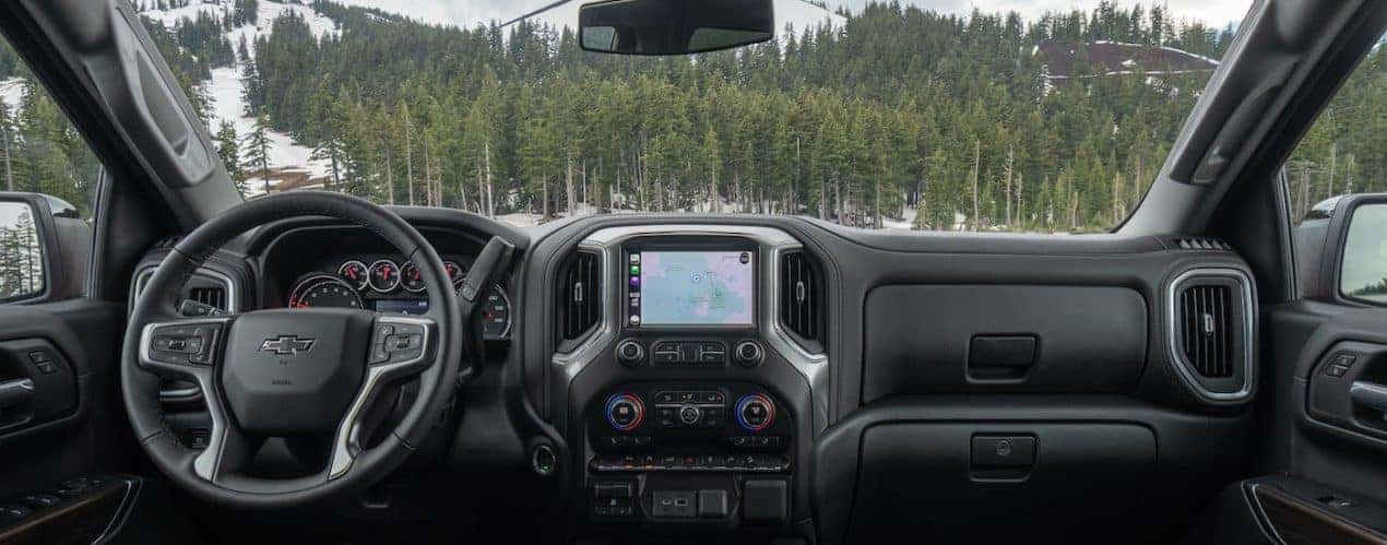 The dashboard of 2021 Chevy Silverado 1500 diesel is shown overlooking evergreen trees after winning the 2021 Silverado Diesel vs 2021 Ram 1500 Diesel comparison.