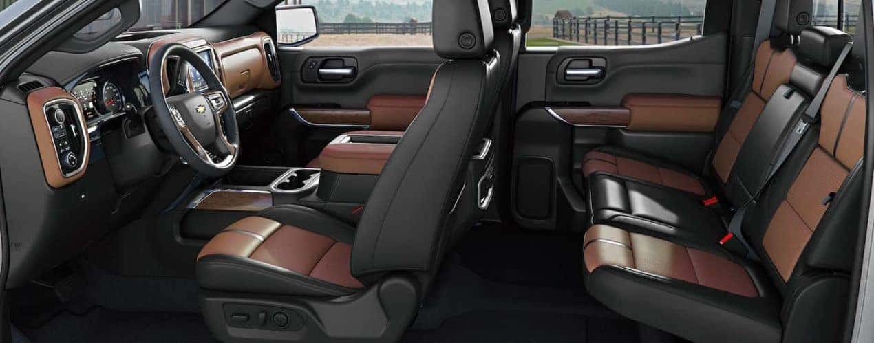 The two rows of brown and black leather seats are shown in a 2021 Chevy Silverado 1500 High Country.