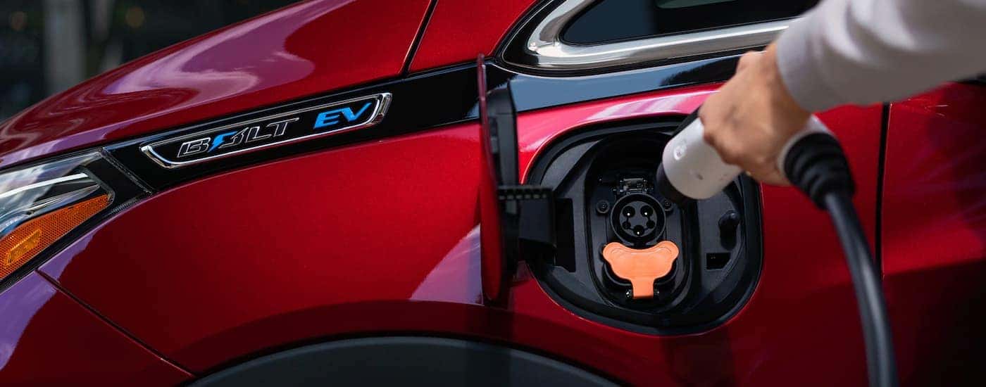 The current Chevy EV, a red 2021 Chevy Bolt EV, has the charging port shown in close up.