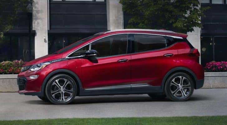 A red 2021 Chevy Bolt EV is shown from the side in front of a grey and black building.
