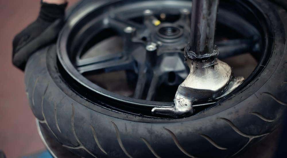 A close up is shown of a black rim having a tire installed on a tire machine.
