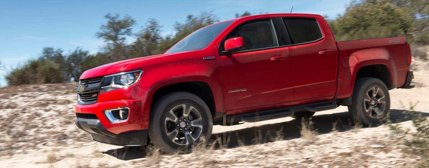 A red 2018 Chevy Colorado with 2.8L Duramax diesel engine is driving on a dirt road.