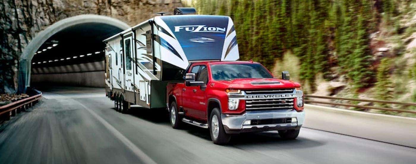 A red 2020 Chevy Silverado 1500 HD is shown towing a trailer.
