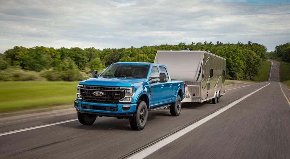 A 2020 Ford F-250 Super Duty Tremor is towing a silver camper down the highway.