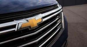 A closeup shows the Chevrolet badging on the grille of a blue 2022 Chevy Equinox at a Chevy Dealer in Cincinnati.