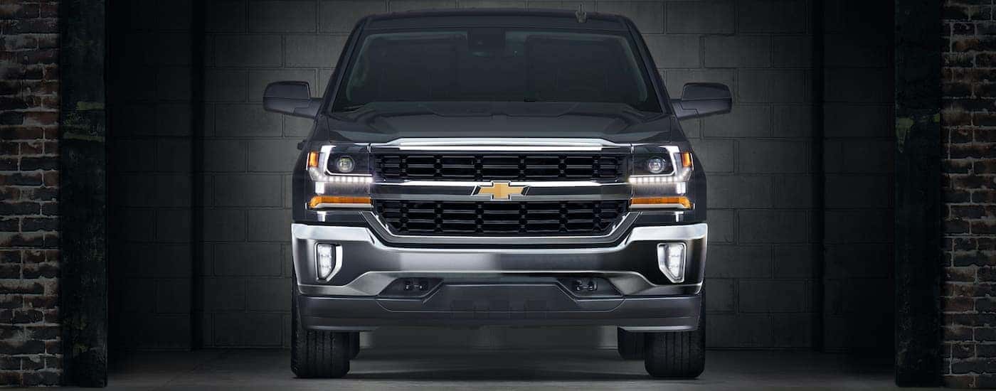 A dark grey 2016 Chevy Silverado Hybrid is shown from the front parked in a brick room.