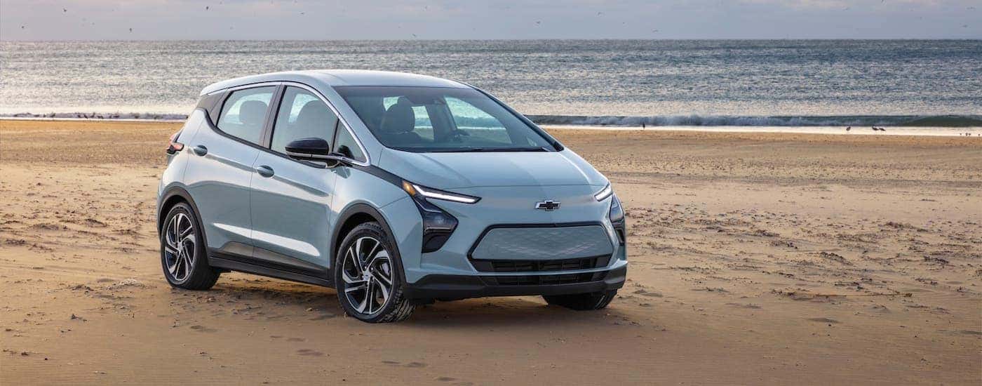 A silver 2022 Chevy Bolt EV is parked on a beach.