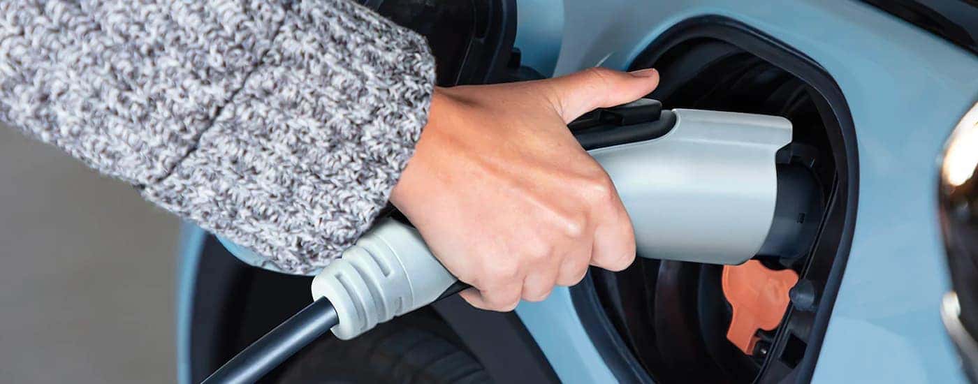 A close up shows a charge cable being plugged into a pale blue 2022 Chevy Bolt EV.