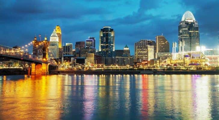 A skyline is shown at night with city lights reflecting off the water.
