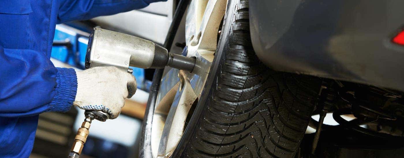 A mechanic is using an impact wrench to put on a tire at a Cincinnati Tire Shop.