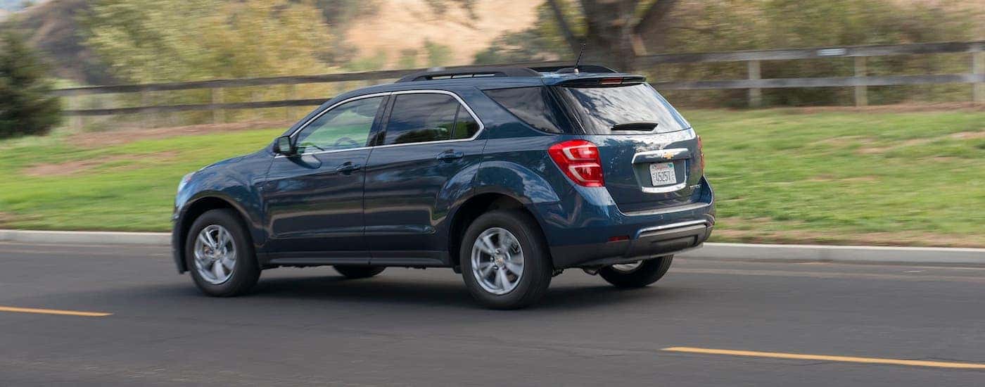A blue 2016 Chevy Equinox is driving on a rural road after leaving an Ohio used car dealer.