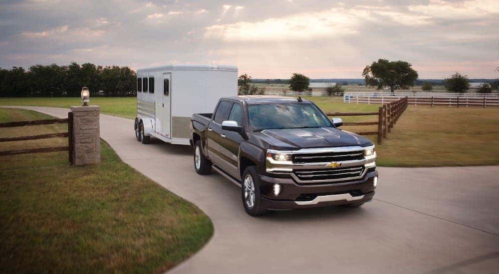 A black 2017 Chevy Silverado 1500 High Country is towing a trailer.