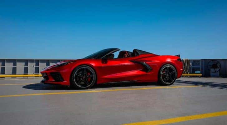 A red 2021 Chevy Corvette is parked in a lot with blue skies in the background, after leaving a used Chevy Dealer.
