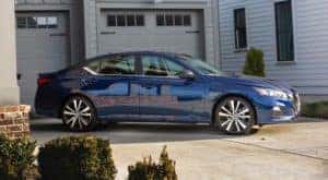 A. blue 2019 used Nissan Altima is parked in front of a garage in a Cincinnati driveway.