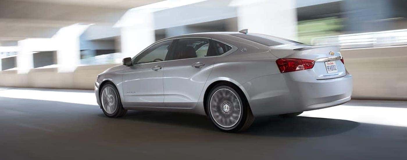 A white 2020 Chevy Impala is shown from the side driving through a tunnel after leaving a used Chevy dealer.