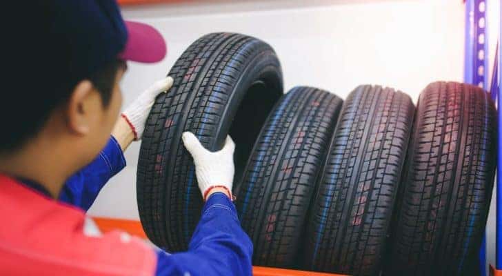 A mechanic is pulling some of the best tires in Cincinnati off of a rack of tires.
