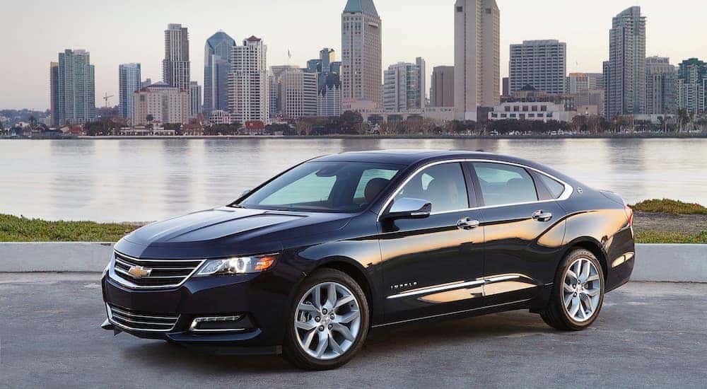 Popular among Cincinnati auto sales, a black 2020 Chevy Impala LTZ, is parked across a river overlooking a city.