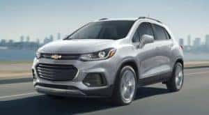 A silver 2021 Chevy Trax is driving away from a city and is popular among Cincinnati auto sales.