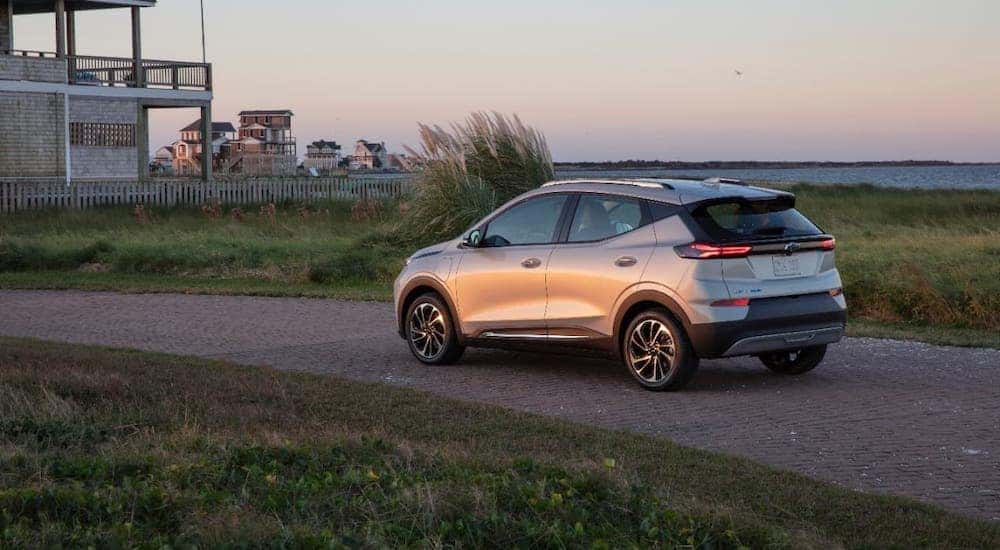 A silver 2022 Chevy Bolt EUV is shown from a rear angle while parked in front of a beach house.