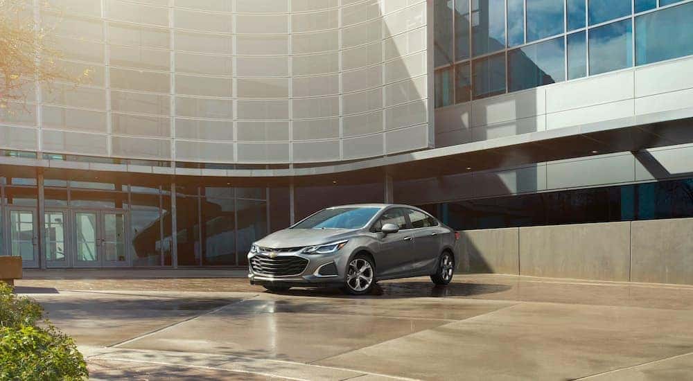 A gray 2019 Chevy Cruze is parked in the courtyard of a modern building.