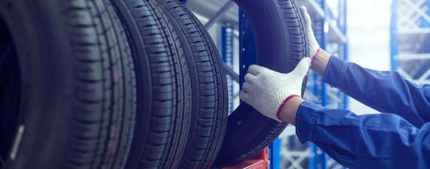 A gloved mechanic is pulling down a new tire.