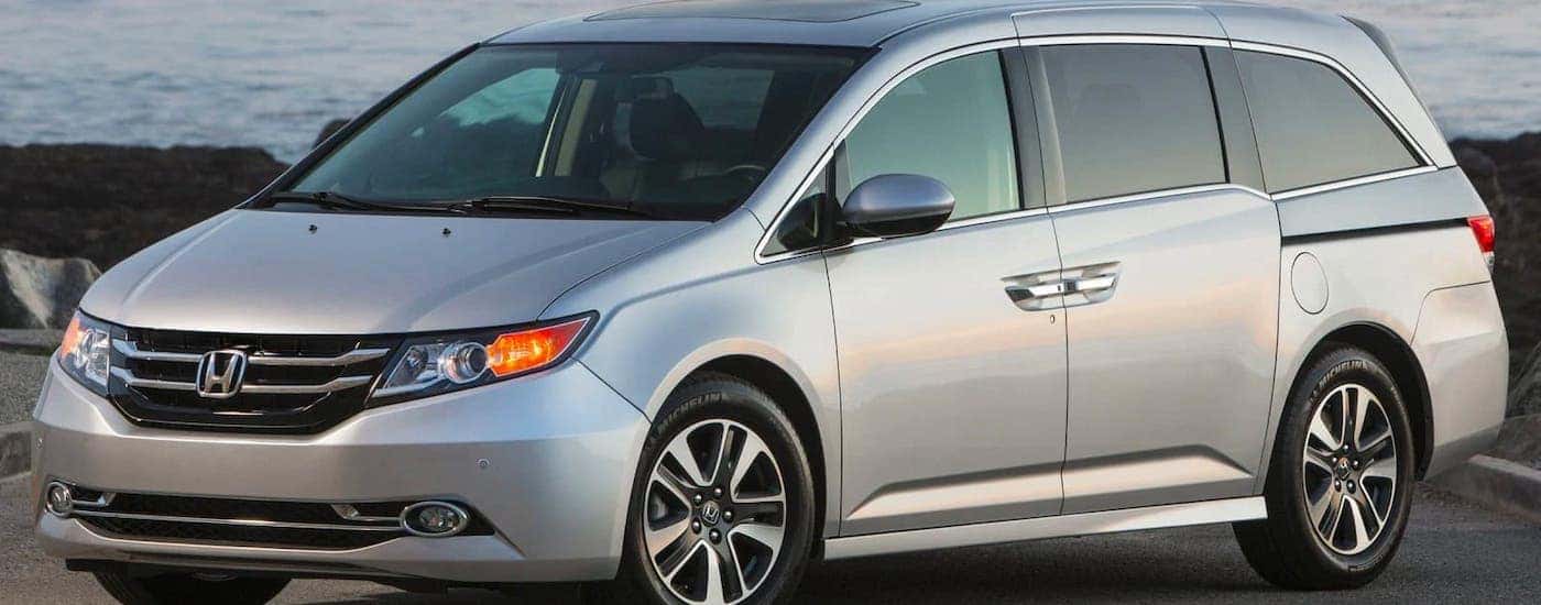 A silver 2015 Honda Odyssey is parked in front of a beach.