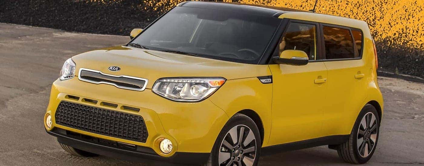 A yellow 2015 Kia Soul is parked in front of a yellow mountain.
