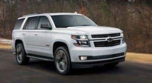 One of the best value used cars, a white 2018 Chevy Tahoe RST, is driving on a road in fall.