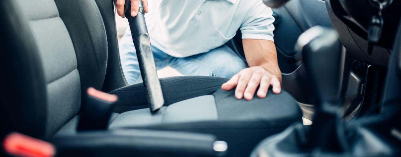A man is vacumming the seat in his vehicle preparing for his Chevy end of lease.