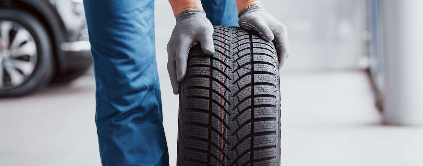 A technician is holding out a summer tire in Cincinnati in a service center.