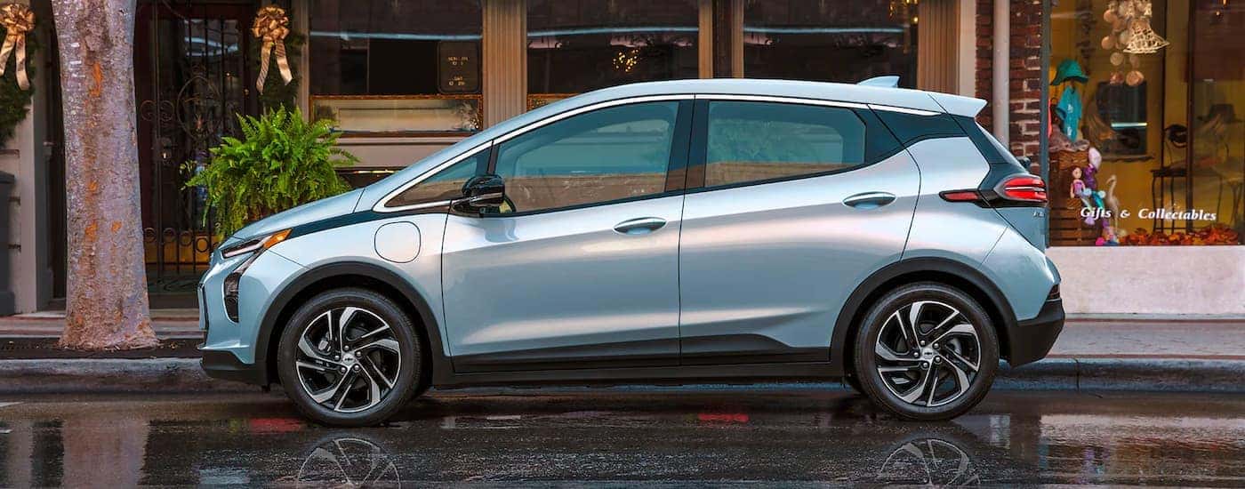 A pale blue 2022 Chevy Bolt EV is shown from the side parked in front of a store.