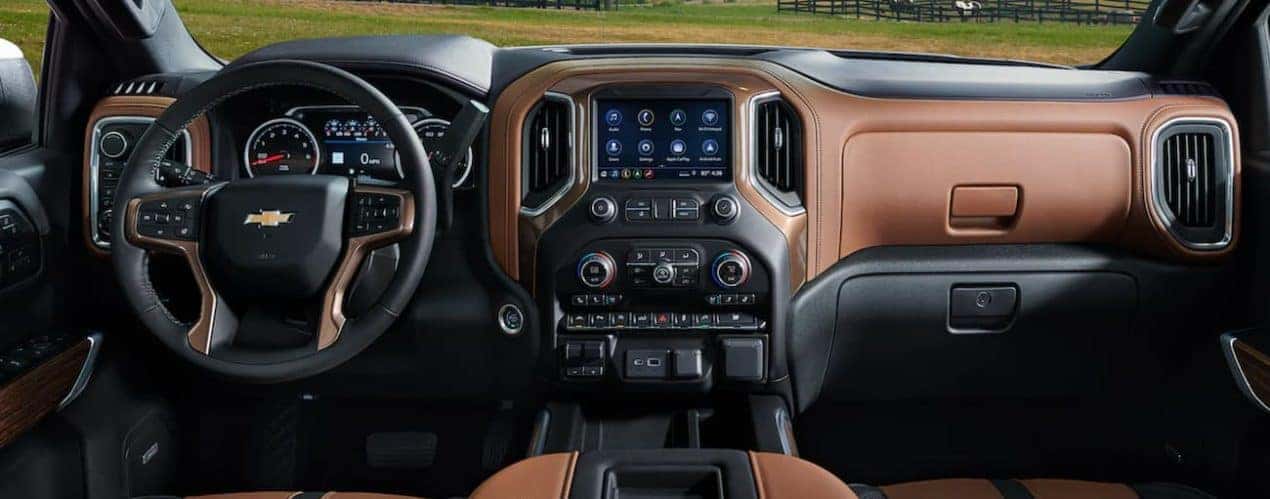 The interior of a 2021 Chevy Silverado 1500 shows the steering wheel and infotainment screen.