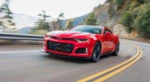 A red 2018 Chevy Camaro ZL1 is driving around a corner after visiting a Cincinnati used car dealership.