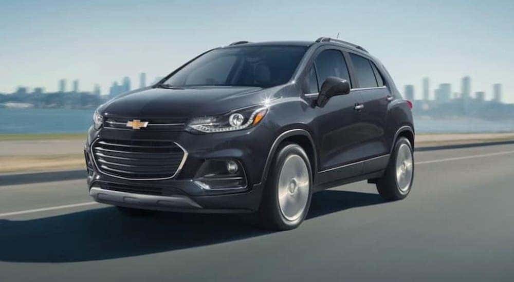 A black 2020 Chevy Trax is shown driving past a city.
