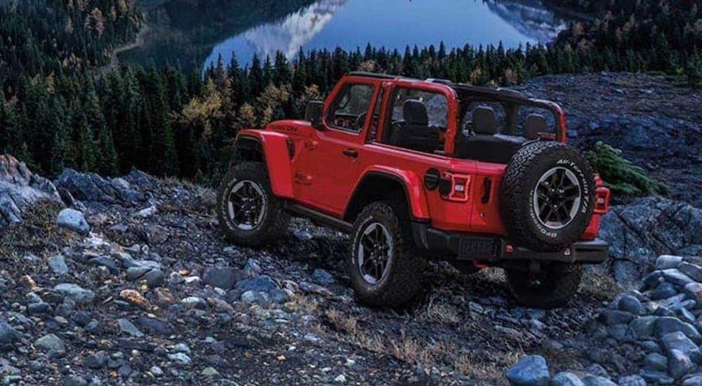 A red 2020 Jeep Wrangler Rubicon is shown from the back parked on rocks in the mountains.