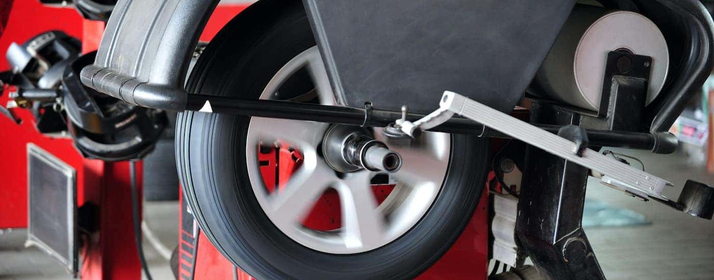 A close up shows a wheel being balanced in a tire machine.