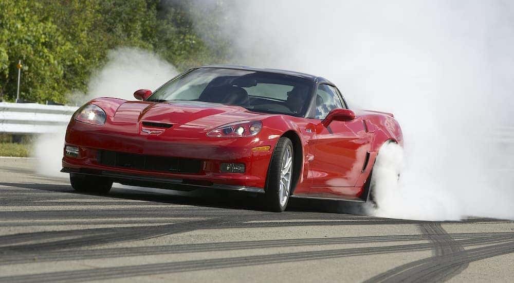 A red 2011 Chevy Corvetee is shown doing a burn out on a race track.