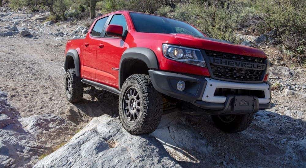 A red 2020 Chevy Colorado ZR2 Bison is shown off-roading on a rocky path.