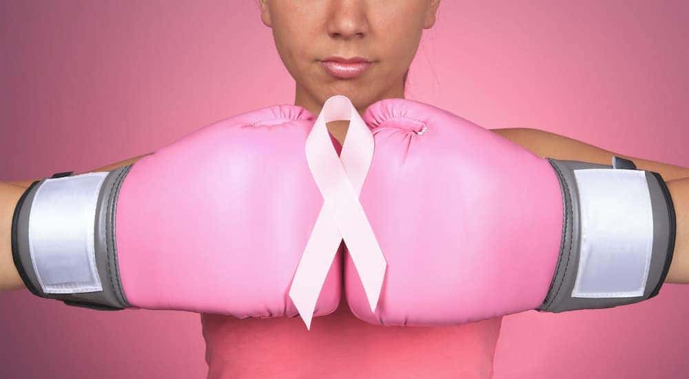 A person is wearing a pair of pink boxing gloves to fight cancer.