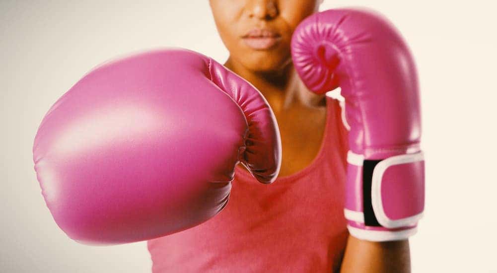 A person is wearing a pair of pink boxing gloves.