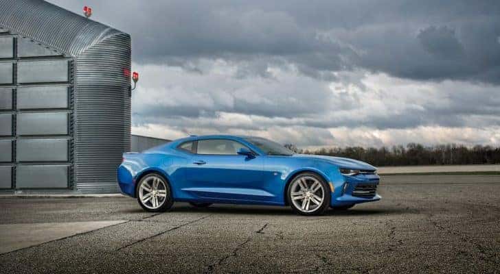 A blue 2016 Chevy Camaro RS is shown parked outside of a hanger.
