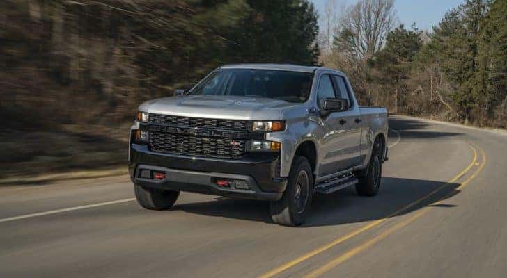 A silver 2020 Chevy Silverado 1500 Z71 Trail Boss is shown driving down an empty road.