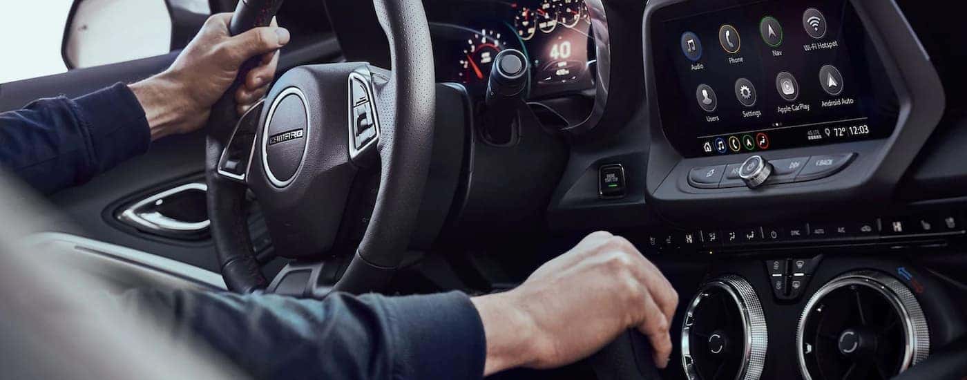 A close up shows a person sitting in a 2022 Chevy Camaro.