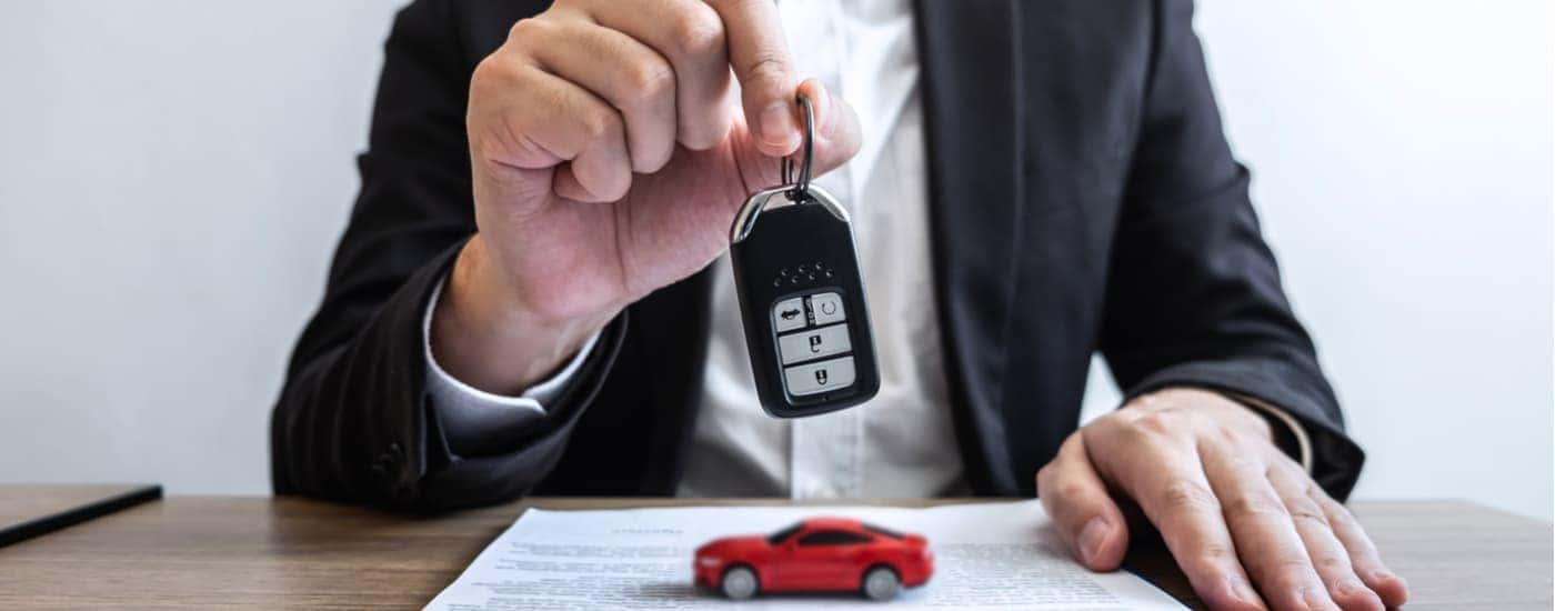 A Chevy pre-order salesman is shown holding a car key at a desk.