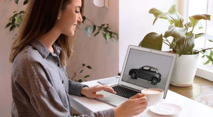 A woman is shown researching information about Chevy pre-order options on a laptop.