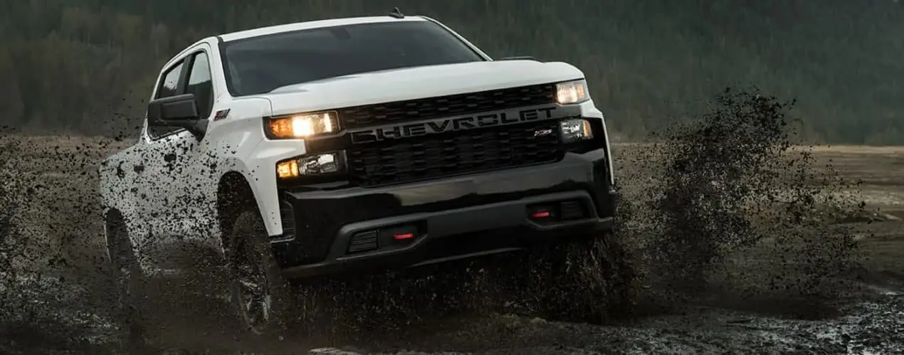 A white 2022 Chevy Silverado 1500 Limited Z71 is shown from the front off-roading in a field.